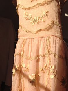 amazing salmon pink chiffon silk flapper dress, used as a wedding dress in 1915  and in 1925this dress has a side closure with snaps and hooks and eyes.the silk dress has a underdress underneath, made of tissue silkthis dress is full of gold silk lace ruffles and with pure silk flower work.this dress is in pretty  good condition, there is a bit staining on the shoulders , but there are no holes no tears, andno underarm discolorations . the silk flower work is beautiful! But the lace ruffles have