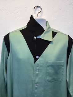 "1950s vintage reproduction Hollywood Rogue two tone mint green and black shirt The shirt has a two tone design with mint green and contrasting black on shoulders and neckline. The garment has a loop collar, five button down front, one patch pocket and long sleeves. The label reads \"Hollywood Rogue\" and the shirt is in new unworn condition. As with all clothes made by \"Hollywood Rogue\" this shirt was made in an original 1950's design and is only available in very limited numbers. Made in Cal Retro Black Tops With Button Closure, Retro Black Tops With Buttons, Black Retro Tops With Buttons, Black Retro Top With Buttons, Retro Black Button-up Shirt, Retro Black Collared Shirt, Retro Green Collared Shirt, Retro Black Tops For Work, Vintage Black Workwear Shirt