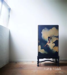 an artistic painting is on display in the corner of a room with white walls and wooden flooring