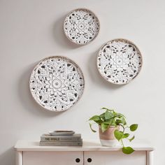 three white plates mounted to the side of a wall next to a potted plant