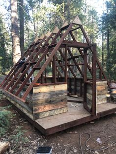 a small wooden structure in the woods with stairs leading up to it's roof