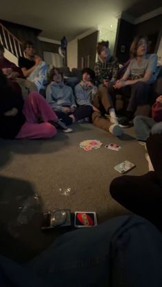 a group of people sitting on the floor in a living room with cards scattered around them