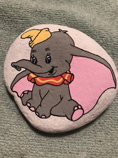 an elephant painted on a rock with a hat and scarf around its neck is shown