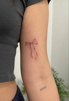 a woman's arm with a tattoo on it that reads oxoxo and has a bow