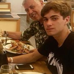 two men sitting at a table with plates of food