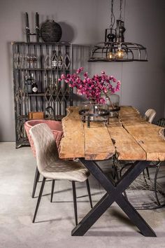 a wooden table with chairs around it and flowers in a vase on the table top