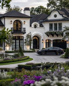 a black car is parked in front of a large white house with lots of windows