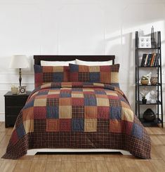 a bed with a brown and blue checkered comforter set on top of it