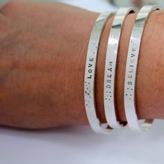 These Message Bracelets with the Word of your choice in Silver are perfect for everyday! Choose from: BREATHE LOVE DREAM BELIEVE ...Or choose CUSTOM WORD and enter the Word you want in notes to me at checkout! At checkout under each item you will see a link to click "Add a note to your order", click it and you will be able to let me know what to stamp If you prefer not to have the dots pattern next to the word, just let me know and I will leave them off. Measures: 4-5mm wide and is adjustable. S Inspirational Engraved Everyday Bracelets, Inspirational Engraved Bracelets For Everyday, Everyday Inspirational Engraved Bracelets, Customizable Meaningful Bracelets For Everyday, Meaningful Everyday Bangle Bracelets, Meaningful Everyday Bangle Jewelry, Everyday Meaningful Bangle Bracelets, Customizable Inspirational Everyday Bracelets, Inspirational Sterling Silver Friendship Bracelets