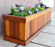 a wooden planter filled with purple and blue flowers on the side of a building