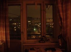 a room with two windows and a view of the city at night