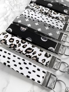 four black and white leopard print key chains on a marble counter with silver metal clasps