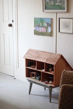 a doll house sitting on top of a wooden table next to a couch and chair