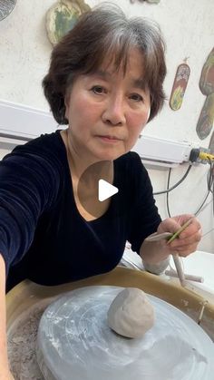 an older woman is working with clay on a wheel and making something out of it