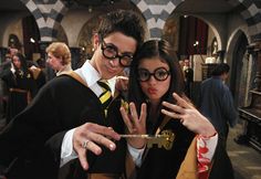 two people dressed in harry potter costumes posing for the camera with their hands up and fingers out