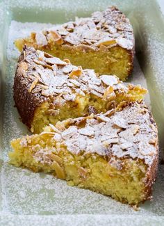 two pieces of cake sitting on top of a pan covered in powdered sugar and almonds