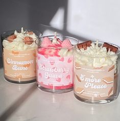 three candles are sitting on a table with some frosting and toppings in them