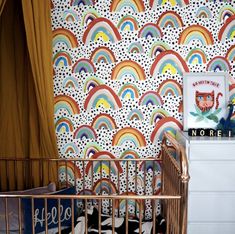 a baby crib next to a colorful wallpaper