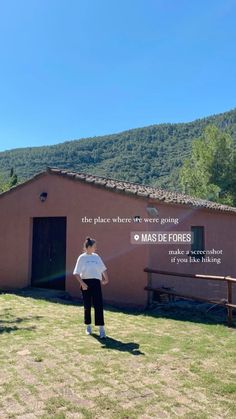 a man standing in front of a pink building with mountains behind him and the words mas de floress written on it