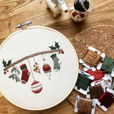 a cross stitch christmas stocking ornament on a wooden table next to some spools of thread