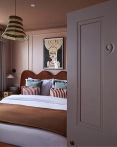 a bedroom with pink walls and a bed in the corner, next to a painting on the wall