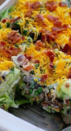 a salad with bacon, cheese and lettuce in a casserole dish