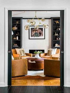 a living room filled with furniture and a fire place under a chandelier hanging from the ceiling