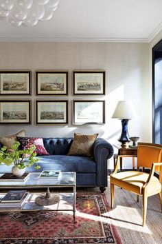 a living room with blue couches and pictures on the wall above them, along with a coffee table