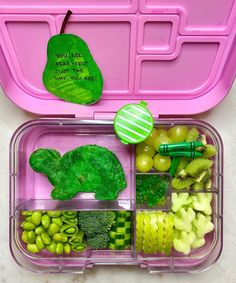 a pink lunch box filled with lots of food next to a green broccoli leaf