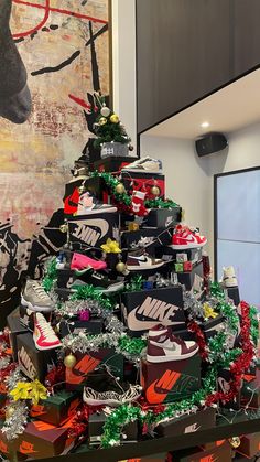 a christmas tree made out of nike shoes in front of a wall with a painting on it