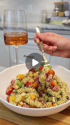 a person is holding a fork over a bowl of pasta with tomatoes and other vegetables