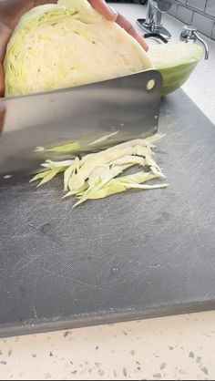 a person cutting up cabbage on top of a counter