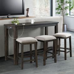 three stools sit in front of a table with a flat screen tv on it