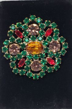 This is a very colorful holiday wreath design brooch. With the perfect holiday color combination of emerald green, ruby red, smoky pink and a large oval citrine color crystal. It is in good vintage condition and is 2 inch in diameter. Enjoy! The majority of the jewelry that I have was my grandmothers and she had a lot and loved wearing them all the time. Thank you so much for looking Please check out my other items at my store. I'm new to this selling on line, I'm not a computer wiz at all LOL, Vintage Multicolor Czech Glass Jewelry, Green Crystal Brooch Jewelry, Czech Jewelry, Vintage Green Rhinestone Brooches, Brooch Dress, Dress Clips, Vintage Multicolor Multi-stone Brooch, Vintage Multi-stone Gold Brooches, Dress Clip