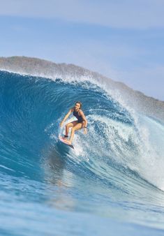 a woman riding a wave on top of a surfboard