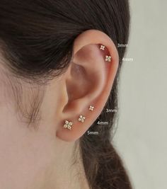 a woman's ear has three small flowers on it and is shown with measurements