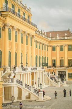 people are walking around in front of a large yellow building with many balconies