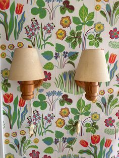 two lamps that are sitting on a wall next to a flowered wallpaper pattern