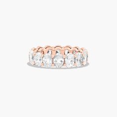 a rose gold ring with five round diamonds on the front and side, set against a white background