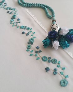 a necklace with blue beads and flowers on the front is laying on a white surface