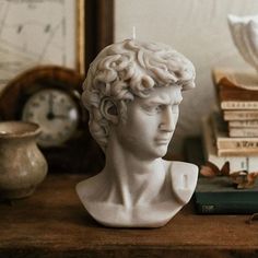 a white busturine sitting on top of a wooden table next to a stack of books