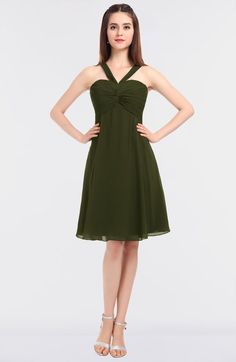 a woman wearing a green dress with a bow at the waist and straps on it