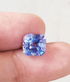 a blue diamond sitting on top of a finger