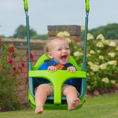 a toddler sitting in a green swing with his mouth wide open and tongue out