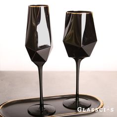 two black wine glasses sitting on top of a tray