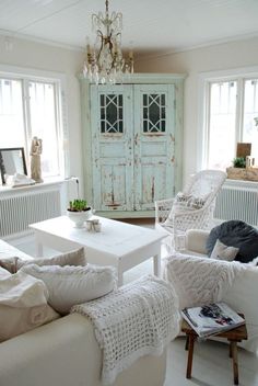 a living room filled with white furniture and lots of windows