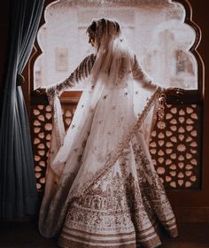 a woman in a bridal gown looking out the window