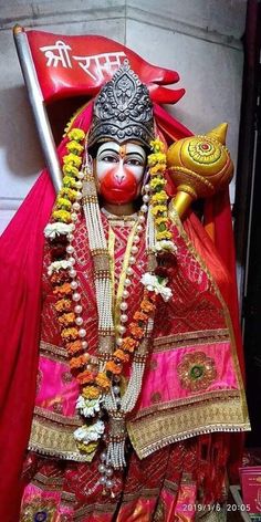 a statue of a person dressed in red and gold with a mask on it's face