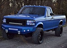 a blue pick up truck parked on a dirt road