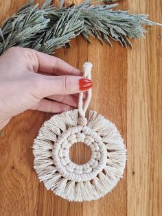 a hand holding a string ornament on top of a wooden table